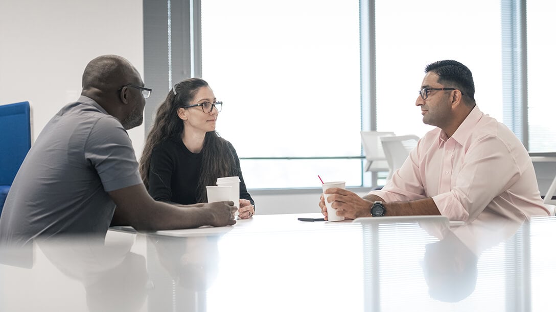 Three Oxy employees at conference table drinking coffee